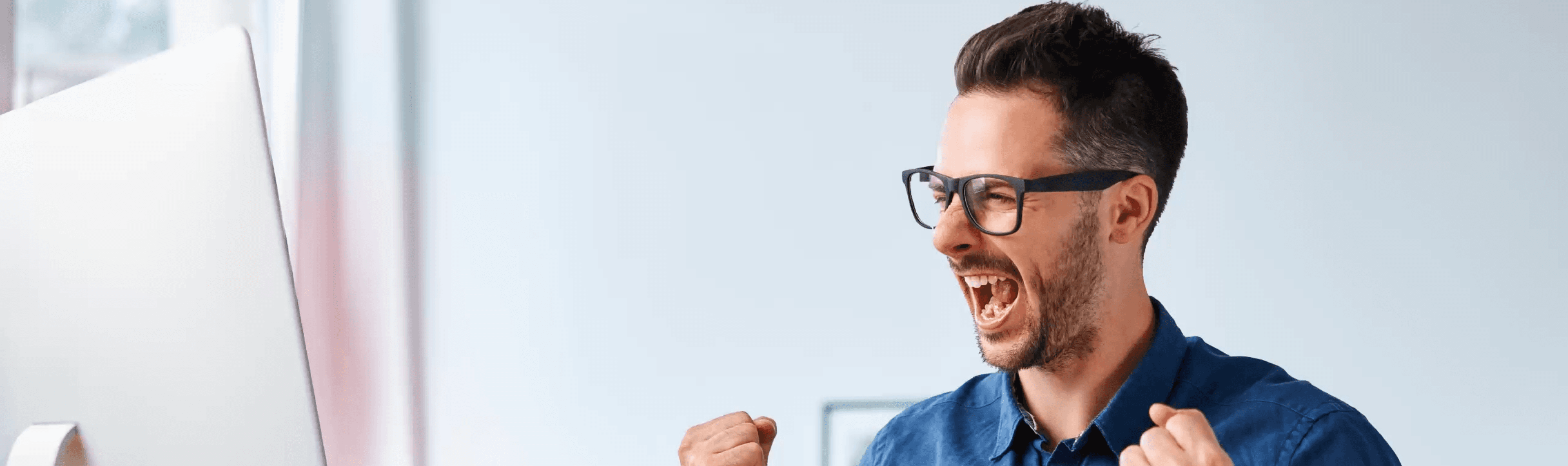 man cheering at computer screen